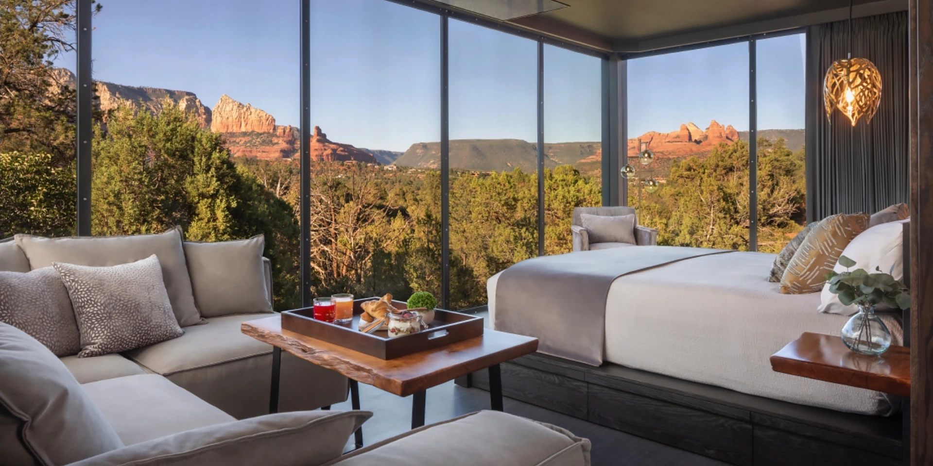 An Atrium suite with a bed, a seating area, and glass walls with a view of Sedona mountains.