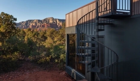Side view of an Atrium at Ambiente with a spiral staircase and views of the red rocks in Arizona in the background.