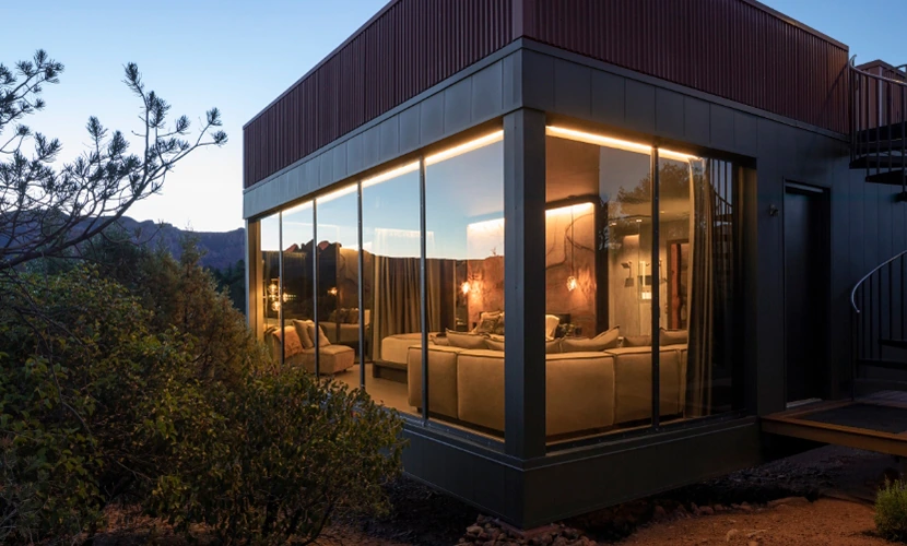 An exterior night view of an atrium with floor-to-ceiling windows, showcasing the Sedona landscape.