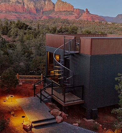 External view of a luxury atrium suite in Sedona with spiral staircase and outdoor lighting, set against the Red Rock mountain.