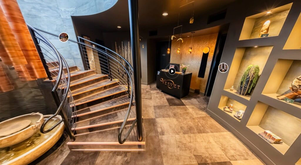 Entrance to Velvet Spa featuring golden hues, with a staircase on the left and a black welcome desk on the right.