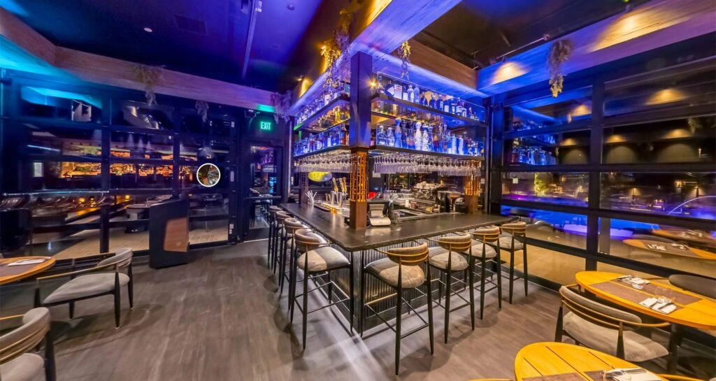 The modern Forty1 restaurant bar with illuminated shelves, barstools, and dining tables in a sleek interior with vibrant lighting.