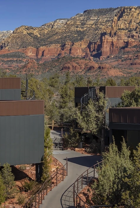 A luxury Arizona resort surrounded by desert vegetation with winding pathways and Sedona's red rock formations in the background.