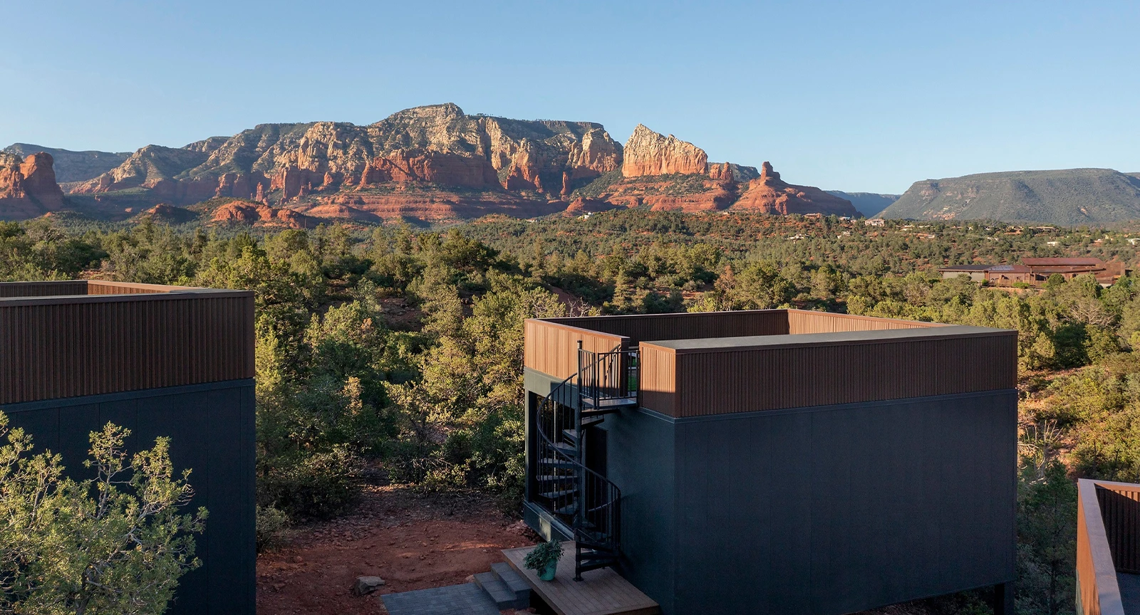 Ambiente Sedona terrace with a view of Sedona's red rock formations and green trees.