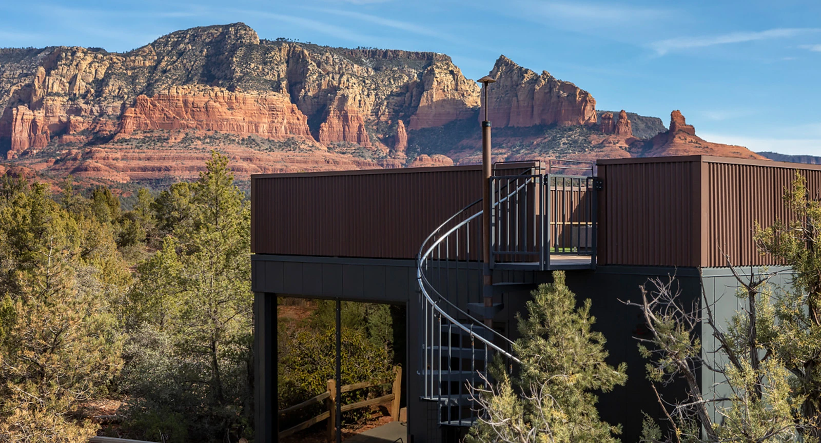 A modern building with a curved staircase and a mountain view