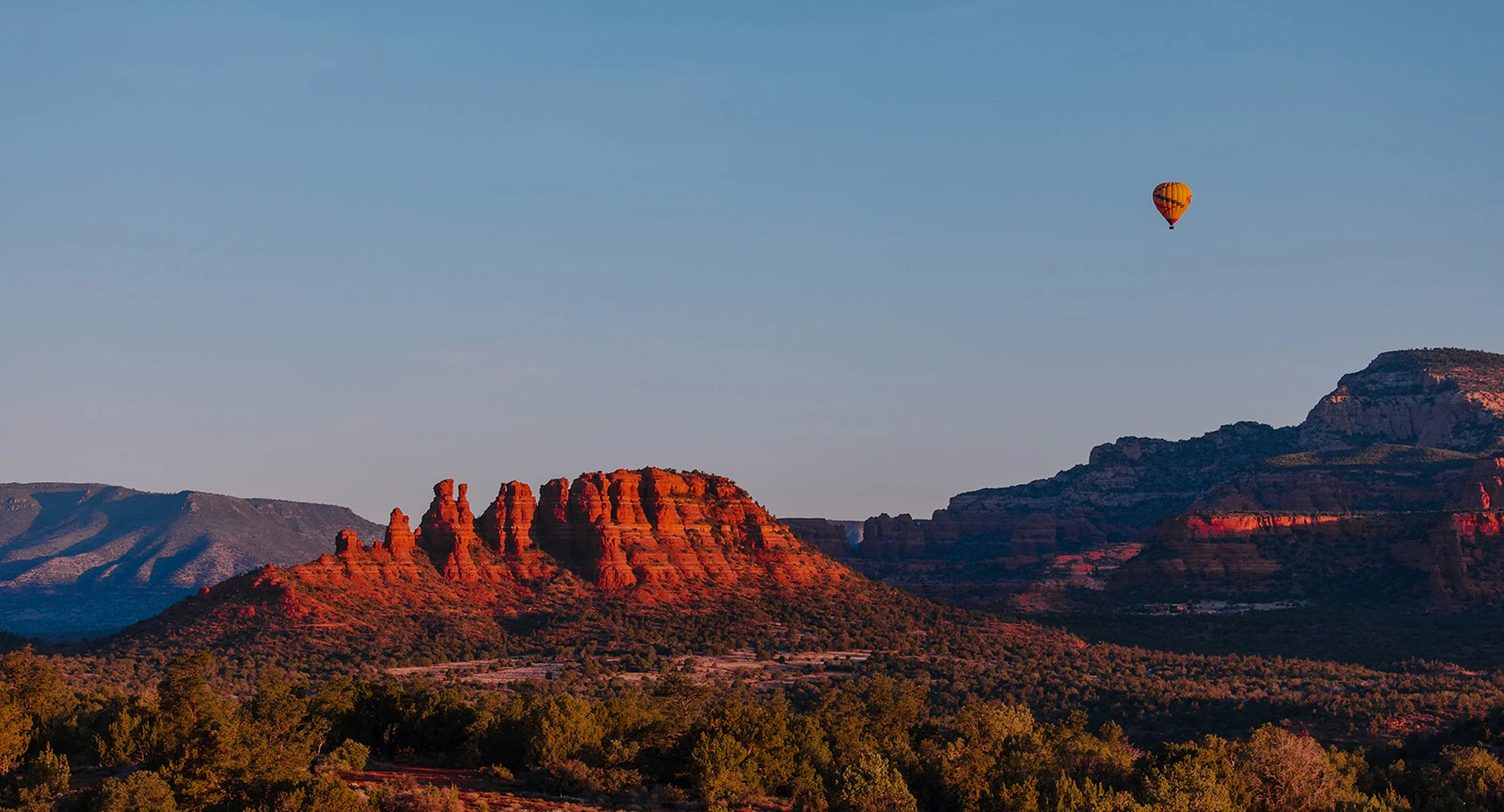 a desert landscape with a hot air balloon floating in the sky