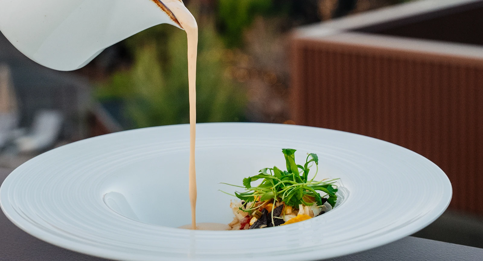 a dish being plated with sauce