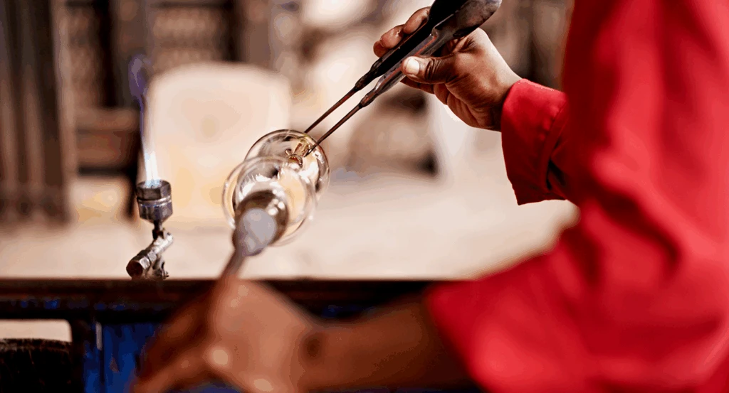 Glass blower with a red shirt crafting a new piece