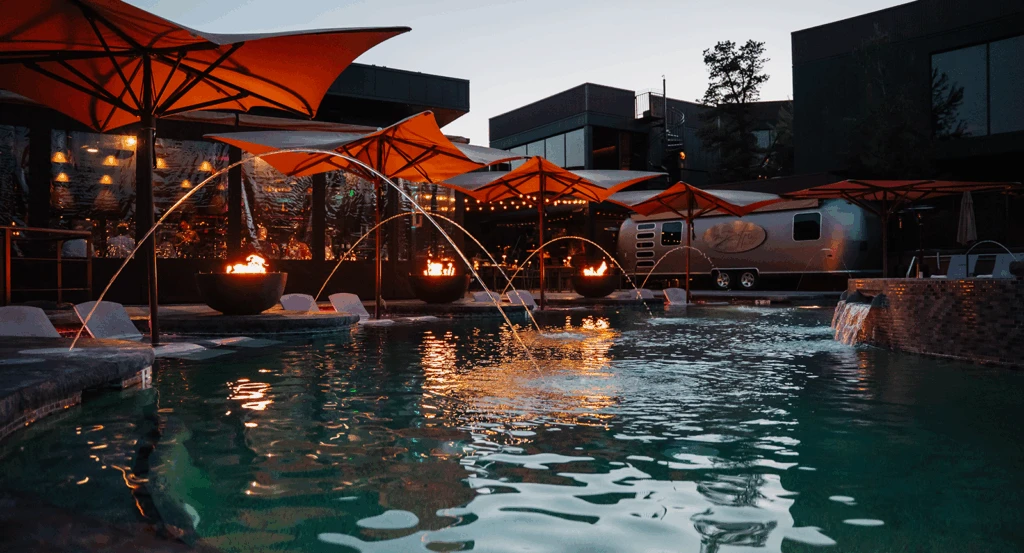 The pool with streams of water and red umbrellas at dusk
