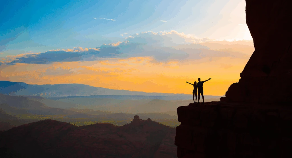 A couple hiking Cathedral Rock at sunrise during a Sedona Arizona honeymoon