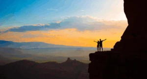 A couple hiking Cathedral Rock at sunrise during a Sedona Arizona honeymoon