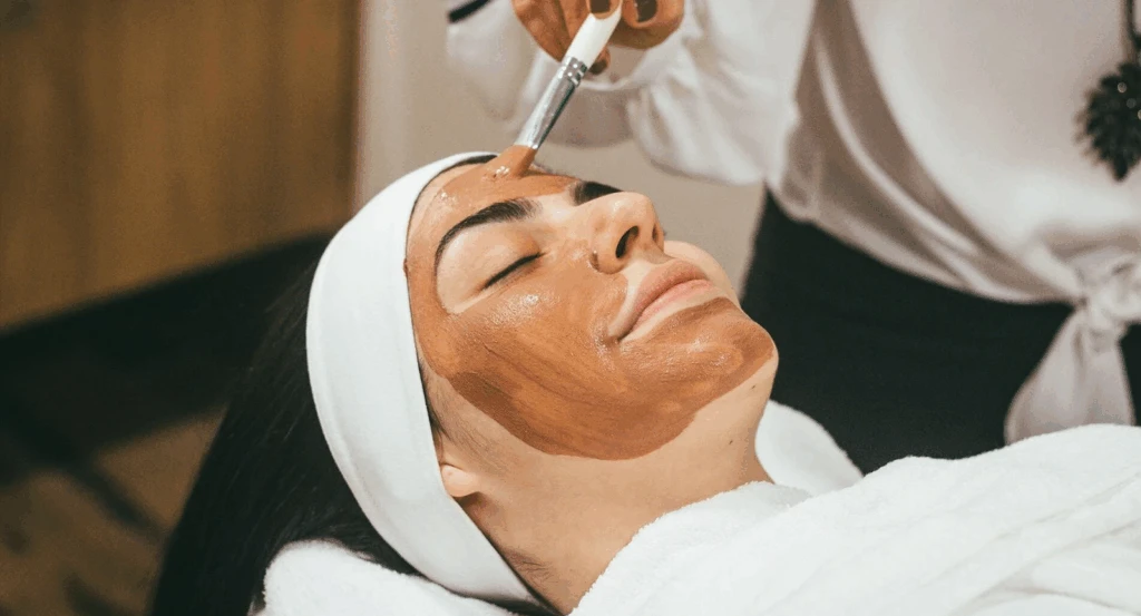 A woman receiving a red clay mask facial 